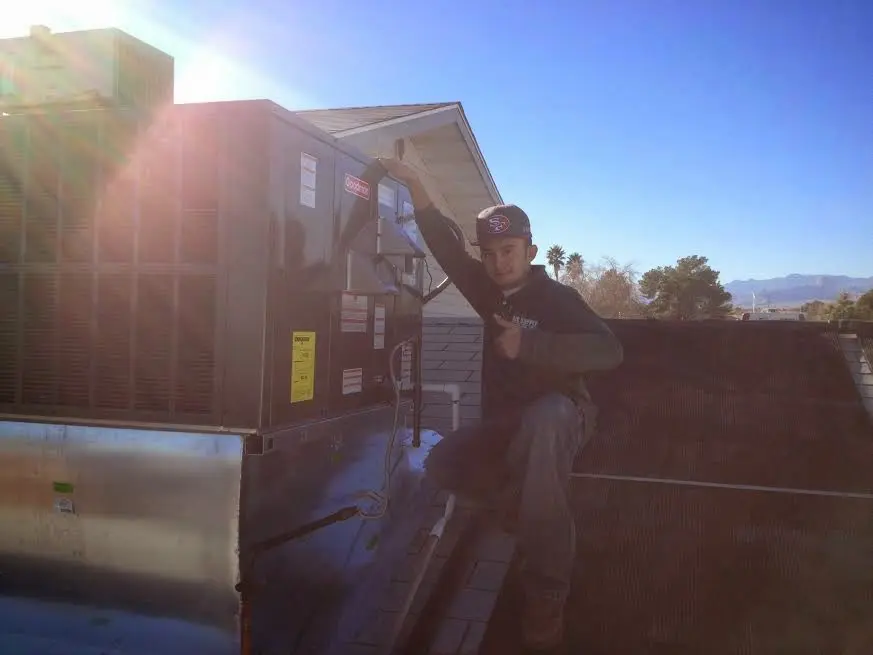 HVAC technician performing AC Tune-Up on a rooftop unit in Galliano