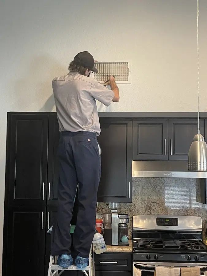 Technician inspecting an air vent during HVAC service in Galliano